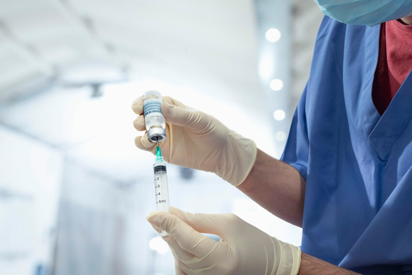 A nurse holds a vial of COVID-19 vaccine and a syringe.