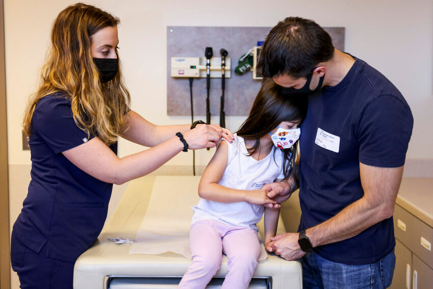 DENVER, CO - NOVEMBER 03: National Jewish Health registered nurse Lindsay Waldman, left, prepares to administer a pediatric COVID vaccine to Emma Waas, 5, as her father, Andy Waas, comforts her on November 3, 2021 in Denver, Colorado. The U.S. Centers for Disease Control has approved the Pfizer-BioNTech pediatric vaccine for the 28 million children aged 5-11 years old. (Photo by Michael Ciaglo/Getty Images)