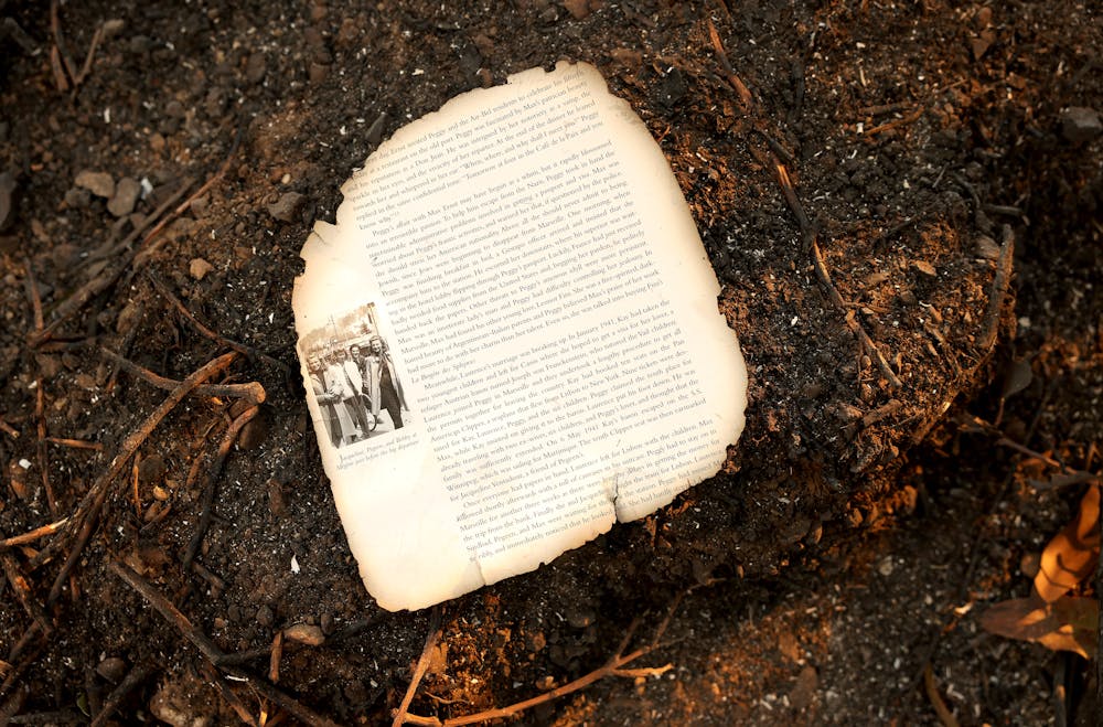 A single page from a book lies on the charred remains of a home that burned down in the 2025 Palisades fire in Los Angeles.